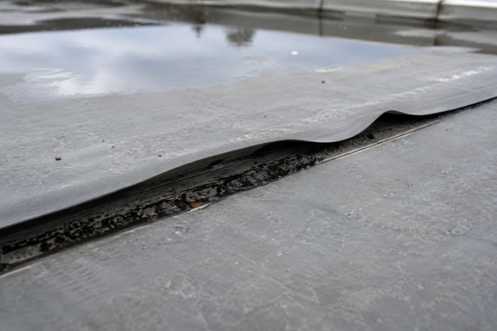 Lifting and separated seam on a flat roof membrane
